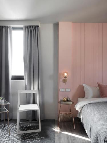 a bedroom with a bed and a chair and a window at Mr.Mantter in Taichung