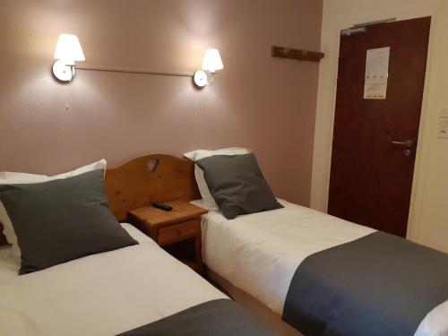 two beds in a room with two lamps on the wall at L'auberge Des 3 Ponts in Cusance