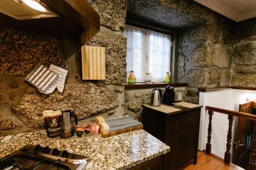 a kitchen with a counter and a stone wall at Casa da Calçada in Guimarães