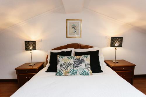 a bedroom with a white bed with two lamps at Casa da Calçada in Guimarães