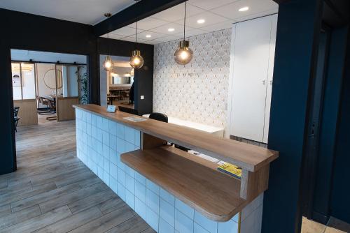 a kitchen with a counter with blue tiles at Hôtel du Beffroi Gravelines Dunkerque in Gravelines