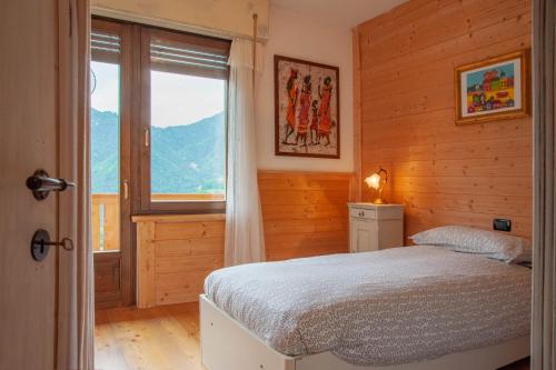 a bedroom with a bed and a large window at Casa Fiore CIPAT 22038 in Canale San Bovo