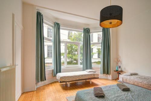 een woonkamer met een groot raam met groene gordijnen bij The National Lodge in Antwerpen