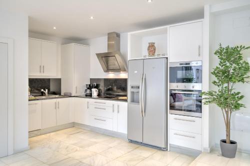 a kitchen with white cabinets and a stainless steel refrigerator at The Antwerp Marble Lodge in Antwerp