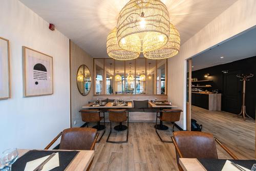 a dining room with a table and a chandelier at Hôtel du Beffroi Gravelines Dunkerque in Gravelines