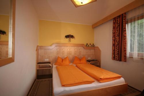 a bedroom with a bed with orange pillows at Ferienhaus Sonnenhang in Matrei in Osttirol