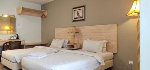 2 camas en una habitación de hotel con sábanas blancas en Prima Hotel Melaka, en Melaka