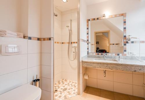 ein Bad mit einer Dusche, einem WC und einem Waschbecken in der Unterkunft Hotel am Fischerhafen in Ditzum