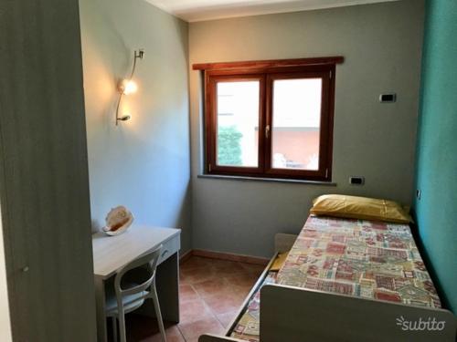Habitación pequeña con cama, escritorio y ventana. en Casa vacanze “Perla del Circeo”, en Sabaudia