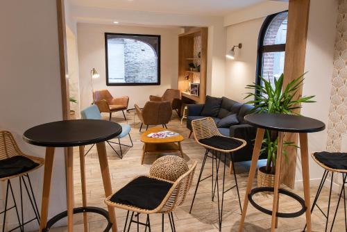 a living room with tables and chairs and a couch at Hôtel du Beffroi Gravelines Dunkerque in Gravelines