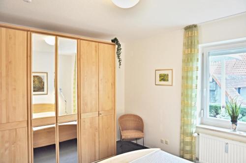 ein Schlafzimmer mit einem Holzschrank und einem Stuhl in der Unterkunft Villa Fördestrand - "Sehpferdchen" in Laboe