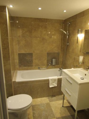 y baño con bañera, aseo y lavamanos. en Le Relais De La Poste, en Pithiviers