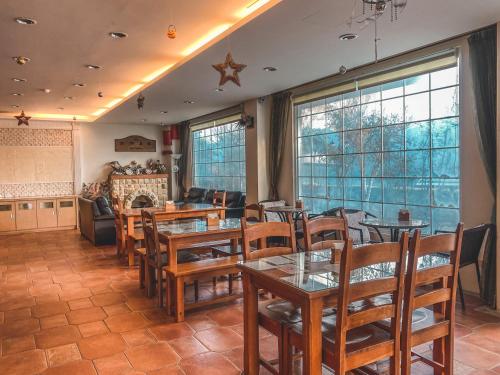 a restaurant with wooden tables and chairs andwindows at Euro Country Villa in Renai