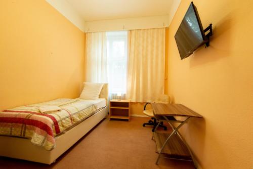 a bedroom with a bed and a television on the wall at Hotel Pension Dahlem in Berlin