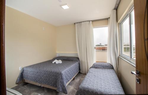 a small room with two beds and a window at Pousada Espindola in Penha