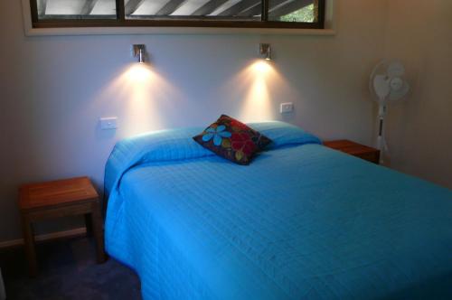 a bedroom with a blue bed with a pillow on it at SPLASH in Elizabeth Beach