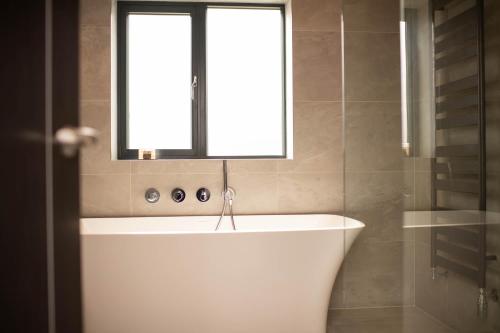 baño con bañera blanca y ventana en Cleabarrow Cottage en Windermere
