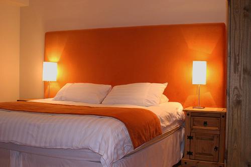 a bedroom with a large bed with an orange headboard at Kingsview Apartment in Stirling
