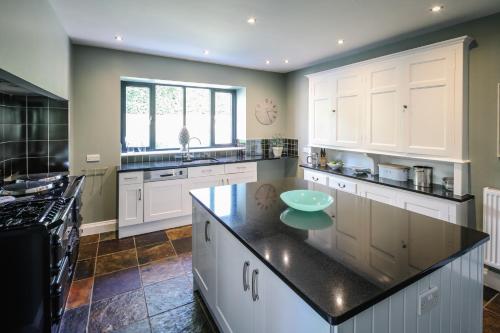 a kitchen with white cabinets and a black counter top at Cherry Trees in Windermere