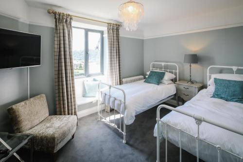 a bedroom with two beds and a tv and a chair at Cherry Trees in Windermere