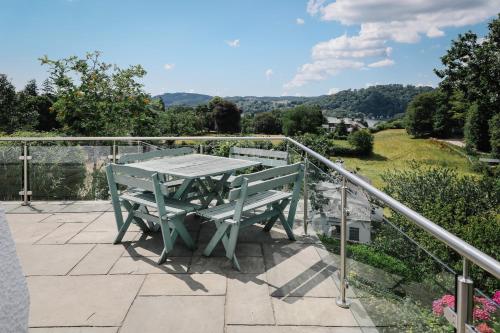 a table and bench on a patio with a view at Cherry Trees in Windermere