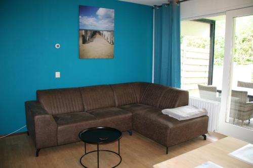 a living room with a brown couch and blue walls at Schorrebloem 10 in Nieuwvliet