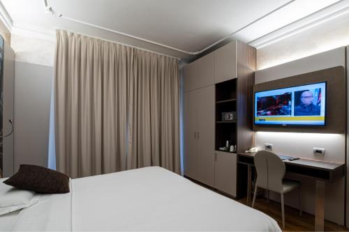 a hotel room with a bed and a desk and a tv at Hotel Mythos in Milan