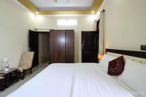 a bedroom with a large white bed and a chair at Touristen Holiday Home A luxury Villa in Dharamshala