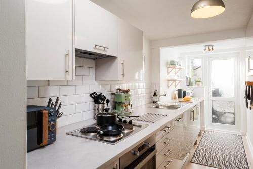 a white kitchen with a stove top oven next to a window at Nomi Homes - Topsham - Exeter - Exmouth Beach - Central - WIFI - BOOKDIRECT in Exeter