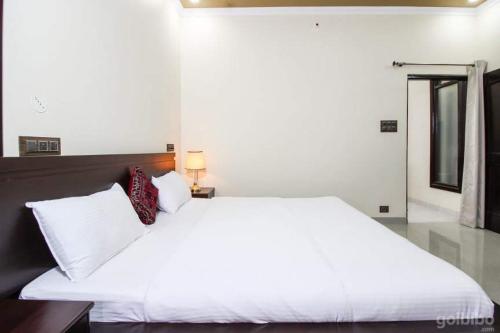 a bedroom with a white bed and a mirror at Touristen Holiday Home A luxury Villa in Dharamshala
