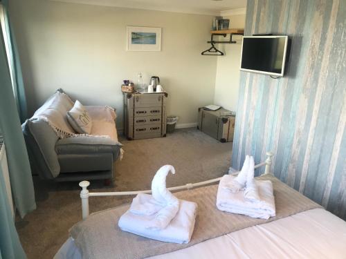 a room with a bed and a couch and a tv at Wellingtons in Fowey