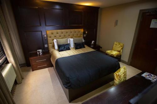 a bedroom with a large bed and a chair at The Crown Hotel Bawtry-Doncaster in Doncaster