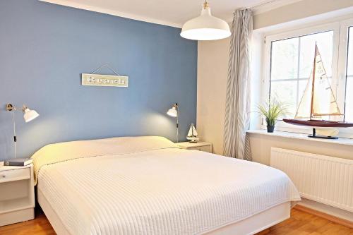 a bedroom with a bed and a window with a sailboat on the wall at Kapitaenshaus 10 in Laboe