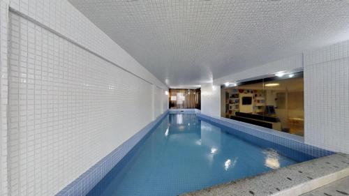 a swimming pool in a building with a tile wall at Camboriú Praia Hotel in Balneário Camboriú