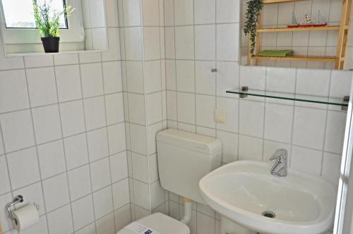 Baño blanco con aseo y lavamanos en Kapitaenshaus 12, en Laboe