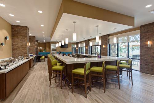 a large kitchen with a large bar with yellow chairs at Holiday Inn Diamond Bar - Pomona by IHG in Diamond Bar
