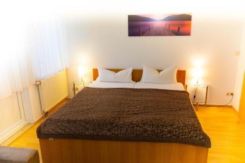 a bedroom with a large bed with two lamps at Hotel am Gutspark Prager GbR in Leipzig