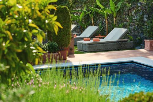 einen Pool mit zwei Liegestühlen neben einem Garten in der Unterkunft Art Hotel Riposo in Ascona