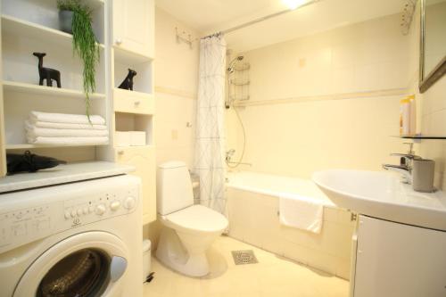 La salle de bains blanche est pourvue d'un lave-linge et d'un lavabo. dans l'établissement Tallinn City Apartments Roosikrantsi, à Tallinn