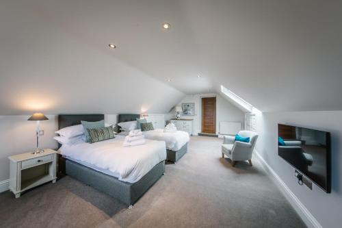 a bedroom with two beds and a flat screen tv at Carus House @ Carus Green in Kendal