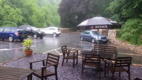 a table and chairs with an umbrella in the rain at High Tor Hotel in Matlock