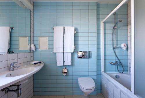 een blauwe badkamer met een toilet en een wastafel bij Green Park Hotel Klaipeda in Klaipėda