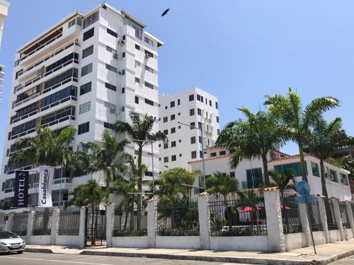 a tall white building with palm trees in front of it at Hotel Casablanca CHIPIPE in Salinas