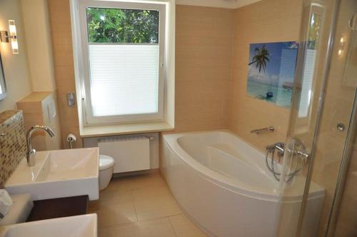 a bathroom with a tub and a toilet and a sink at Villa Bellevue I in Heikendorf