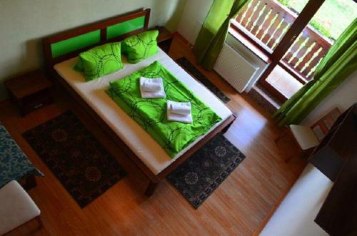 a bedroom with a bed with green sheets and pillows at Rodinný penzión Rogalo in Mengusovce