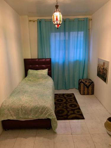 1 dormitorio con cama y cortina azul en Gueliz Imane Centre Américain, en Marrakech