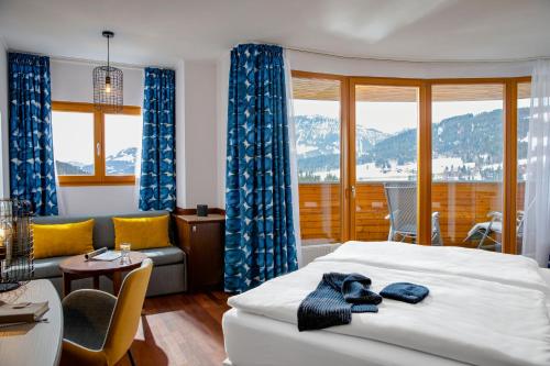 a bedroom with a bed with blue curtains and a couch at TUI BLUE Fieberbrunn in Fieberbrunn