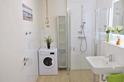 een witte badkamer met een wasmachine en een wastafel bij Sommerbrise Wallbox in Laboe