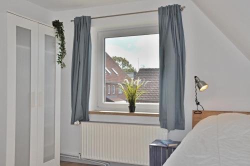 a bedroom with a window with blue curtains at Strandhaus 19b in Laboe