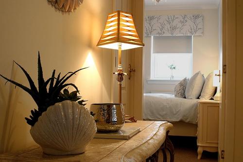 a bedroom with a bed and a table with a lamp at Linden Apartment in Stirling